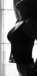 Woman in silhouette by window, highlighting confidence and elegance for breast lift options.