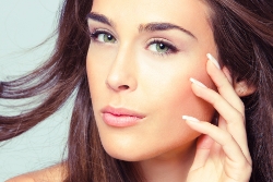 Beautiful woman gently touching her face, highlighting youthful skin and elegance.