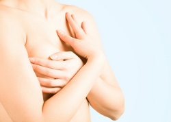 Woman covering breasts, emphasizing breast revision and care at Lentz Plastic Surgery.