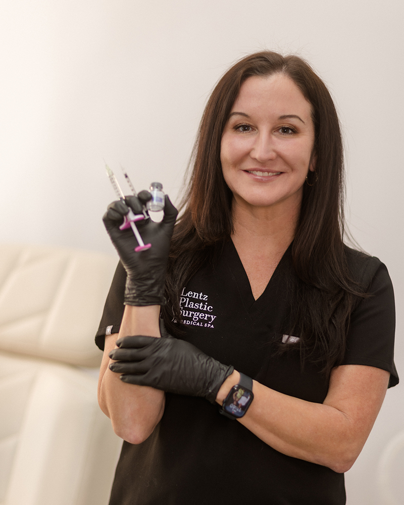 Professional aesthetic provider at Lentz Plastic Surgery & Medical Spa wearing black scrubs and holding cosmetic injection syringes.